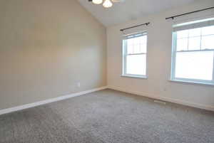 Carpeted spare room with plenty of natural light, vaulted ceiling, and baseboards