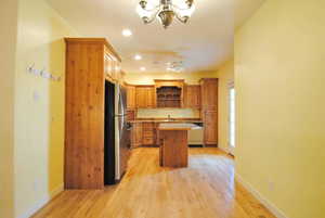 Kitchen with appliances with stainless steel finishes, open shelves, a sink, a chandelier, and light countertops