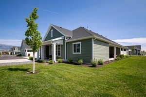 View of front of home featuring a front yard, board and batten siding, concrete driveway, and roof with shingles
