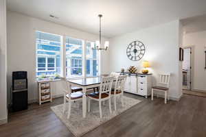Dining space featuring dark wood-style flooring, a chandelier, and baseboards