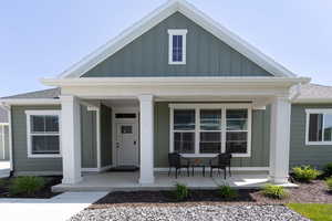 View of front of property with covered porch, board and batten siding, and roof with shingles