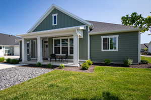 View of front of home featuring a porch, board and batten siding, a front lawn, and roof with shingles