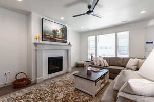 Living room with a ceiling fan, a tiled fireplace, recessed lighting, wood finished floors, and baseboards