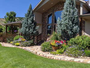 View of side of home featuring stone siding and a lawn