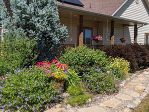 Doorway to property featuring a porch, solar panels, and a shingled roof