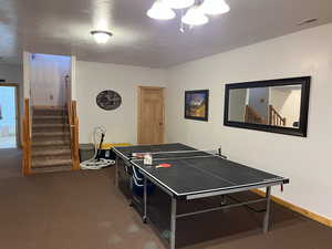 Playroom with carpet floors, baseboards, and a textured ceiling