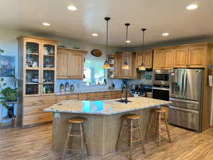 Kitchen featuring stainless steel appliances, a sink, light wood-type flooring, light stone countertops, and recessed lighting