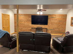 Carpeted living area with wood walls, a ceiling fan, and recessed lighting