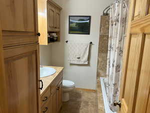 Full bath featuring toilet, vanity, and baseboards