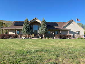 View of front of house featuring roof mounted solar panels and a front lawn