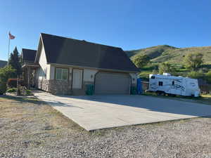View of front facade with an attached garage, concrete driveway, a mountain view, and stone siding