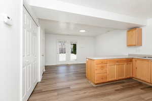 Kitchen with light wood-style floors, a peninsula, light countertops, and light brown cabinetry