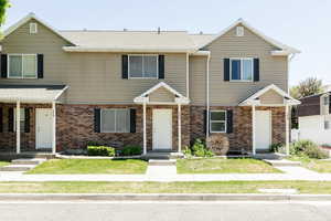 Multi unit property featuring brick siding and a front yard