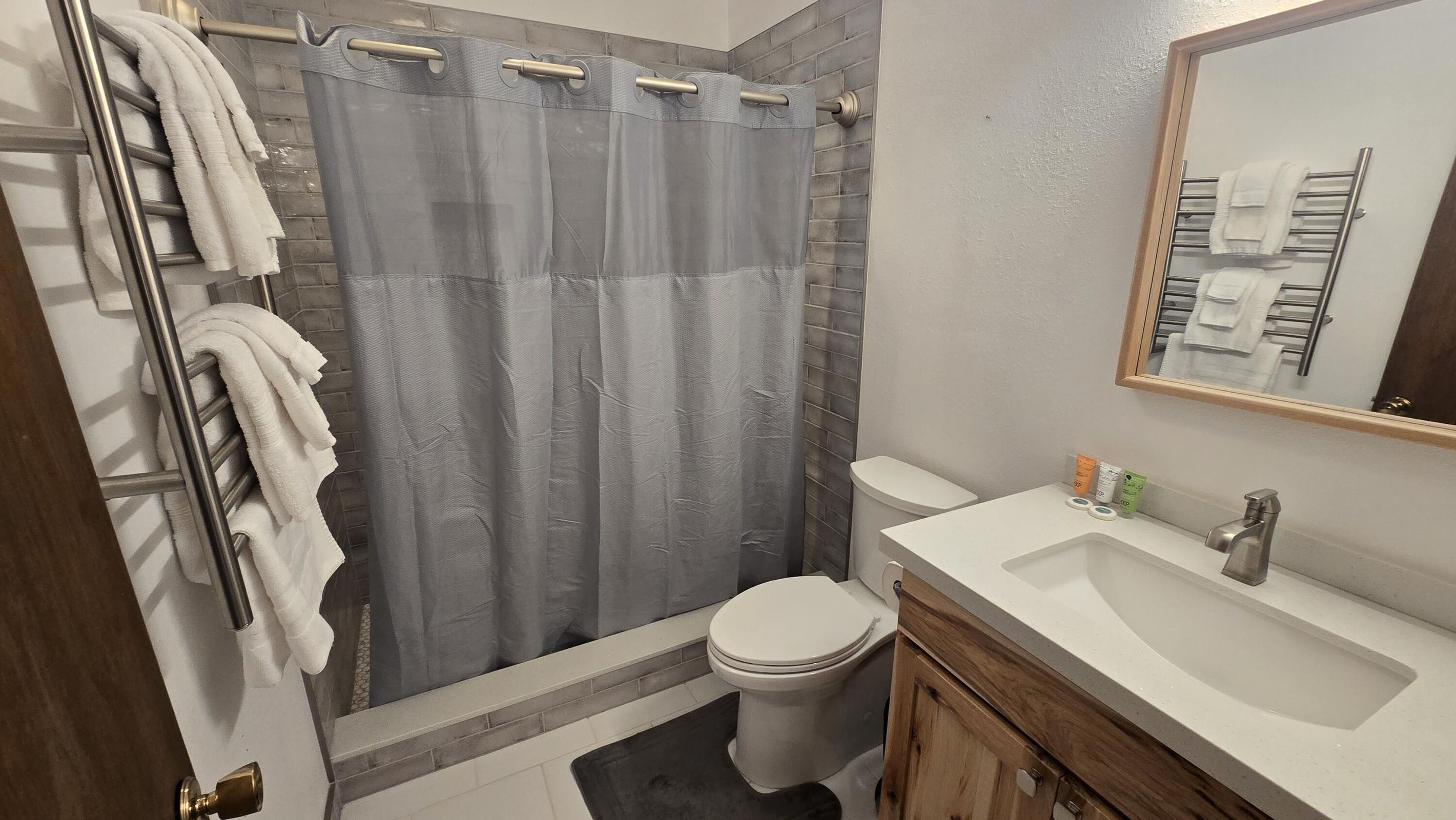 Bathroom featuring radiator, vanity, toilet, a towel warming rack, and curtained shower