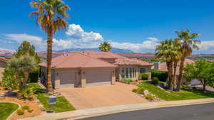 Mediterranean / spanish-style house with an attached garage, stucco siding, driveway, a tile roof, and a mountain view