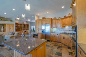 Kitchen with stainless steel appliances, a sink, open floor plan, decorative backsplash, and recessed lighting