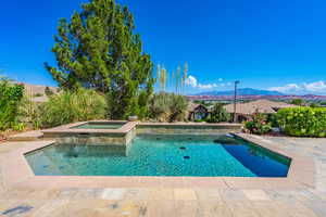 Outdoor pool with an in-ground hot tub, a mountain view, and a patio