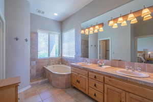 Full bath featuring a bath, double vanity, and tile patterned floors