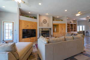 Living area featuring a ceiling fan, recessed lighting, a fireplace, and a textured ceiling