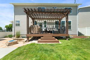 Rear view of house featuring a wooden deck, a pergola, and a patio