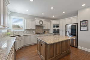 Kitchen with stainless steel appliances, a sink, a center island, white cabinetry, and tasteful backsplash