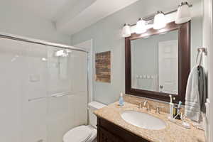 Bathroom with a shower stall, toilet, and vanity