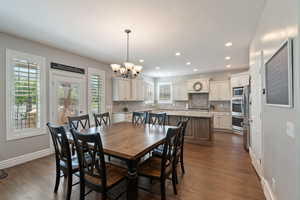 Dining space featuring dark wood-style flooring, a chandelier, recessed lighting, and baseboards