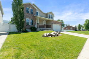 View of front of house featuring brick siding, concrete driveway, an attached garage, stucco siding, and a gate