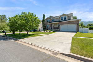 Traditional home with concrete driveway, a garage, brick siding, and a mountain view