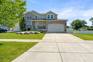 Traditional-style house with concrete driveway, a garage, stucco siding, a porch, and brick siding