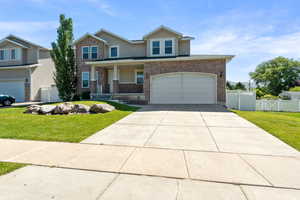 View of front of house with an attached garage, driveway, stucco siding, brick siding, and a porch