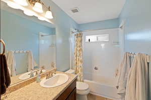 Full bath featuring toilet, shower / bath combo with shower curtain, and vanity