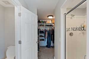 Full bathroom with a stall shower, a spacious closet, and toilet