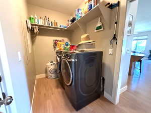Laundry area featuring separate washer and dryer, light wood finished floors, and baseboards