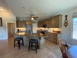 Kitchen with stainless steel appliances, a sink, decorative backsplash, and a kitchen bar