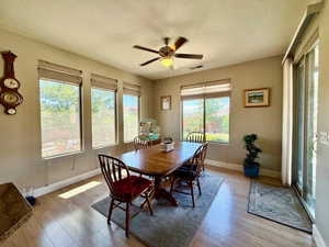 Dining space featuring wood finished floors, baseboards, a textured ceiling, and ceiling fan