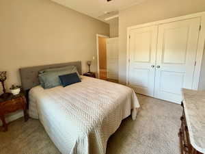 Bedroom with light carpet, a closet, and ceiling fan