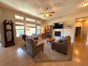 Living area featuring a tile fireplace, wood finished floors, a ceiling fan, and baseboards