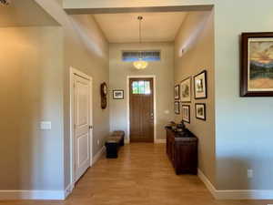 Foyer featuring light wood-style floors, a towering ceiling, and baseboards