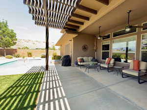 Fenced backyard with outdoor lounge area, ceiling fan, and a patio area