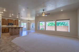 Kitchen featuring stainless steel appliances, open floor plan, brown cabinetry, a chandelier, and recessed lighting