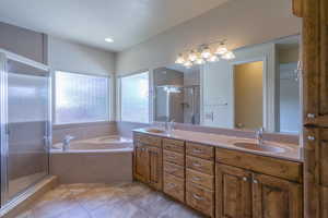 Full bathroom featuring double vanity, a stall shower, and a bath