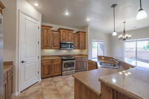 Kitchen featuring stainless steel appliances, brown cabinetry, a sink, pendant lighting, and recessed lighting