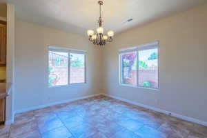 Unfurnished room with a chandelier and baseboards