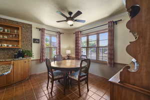 Tiled dining area featuring a ceiling fan, crown molding, and baseboards