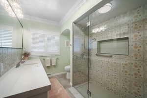 Bathroom featuring vanity, a stall shower, toilet, crown molding, and a baseboard radiator