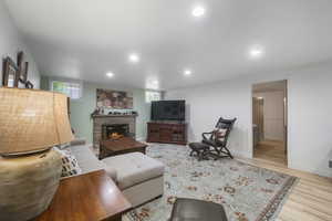 Living room featuring plenty of natural light, wood finished floors, a lit fireplace, recessed lighting, and baseboards