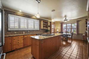Kitchen featuring a sink, tasteful backsplash, tile patterned floors, ornamental molding, and a ceiling fan