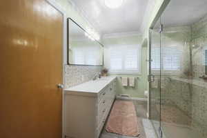 Bathroom with vanity, a shower stall, toilet, crown molding, and tile patterned floors