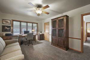 Carpeted office featuring ceiling fan and baseboards